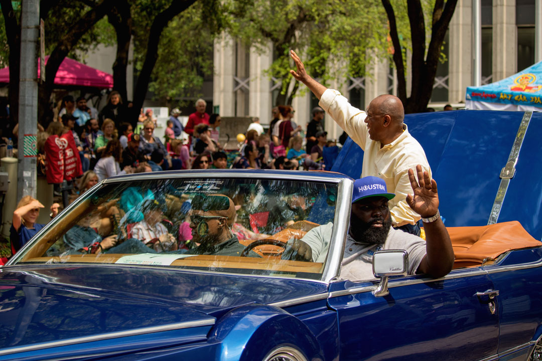 a picture of Mayor Sylvester Turner in the back seat of a brightly painted classic convertible