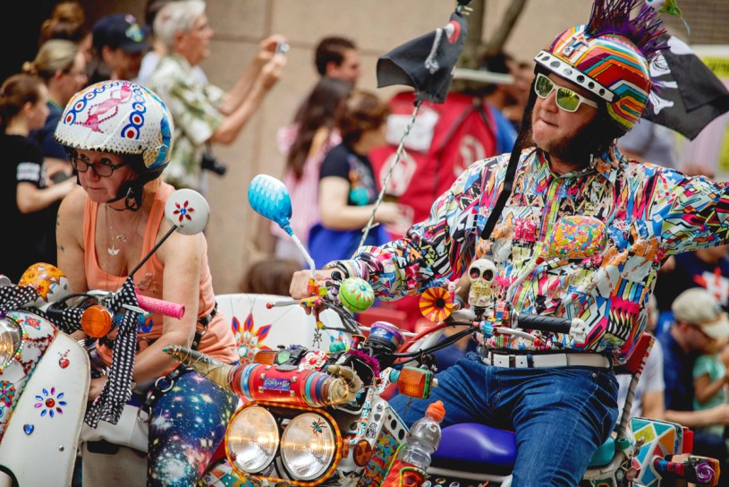 a picture of a couple riding scooters wearing eccentric costuming